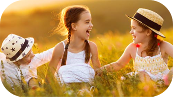 Two young girls with little brother laughing in a field of tall growth.
