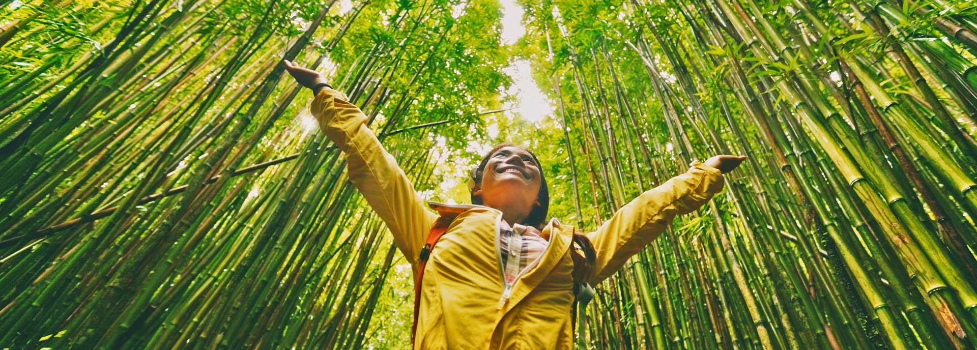 Girl in a field of bamboo smiling with outstretched arms.