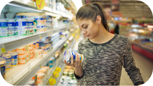 Teen age girl at grocery store looking at dairy product label.
